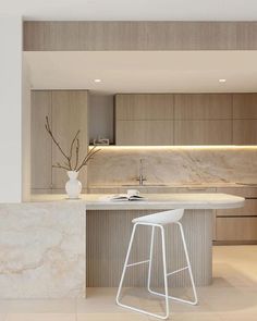 a modern kitchen with marble counter tops and white stools