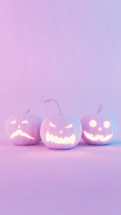 three pumpkins with glowing faces on them in front of a pink background and one is lit up