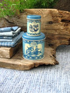 a blue and white container sitting on top of a piece of wood next to a stack of folded towels