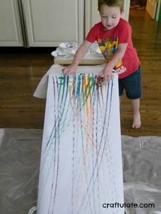 a young boy standing in front of an art project with crayons on it