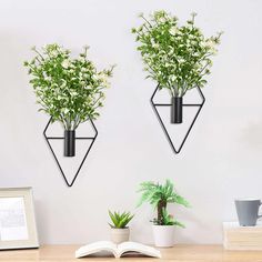 two planters are hanging on the wall next to a book and potted plant