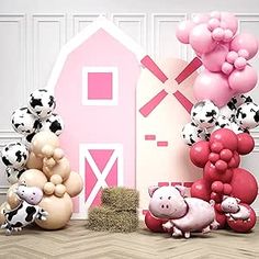 some balloons are in the shape of farm animals and a pink barn with black and white polka dots