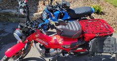 a red motorcycle parked on the side of a road next to a pile of luggage