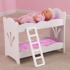 a baby doll laying on top of a white bunk bed with pink sheets and pillows