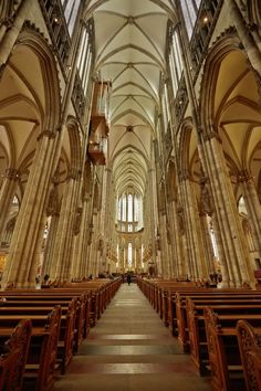 the inside of a large cathedral with pews and stained glass windows on both sides