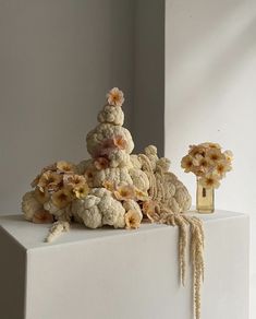 an arrangement of crocheted flowers and vases on a white surface with light coming through the window