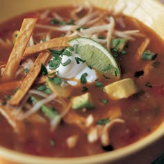 a bowl of chili soup with tortilla chips and sour cream