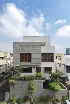 an aerial view of a modern house with trees and plants on the roof, surrounded by buildings