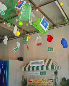 an assortment of items hanging from the ceiling in a market area with green and white striped awnings