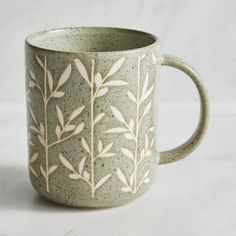 a ceramic mug with leaves painted on the outside and inside, sitting in front of a white background