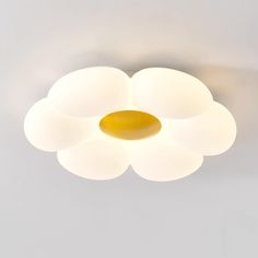 a white flower shaped light fixture on a gray ceiling with yellow accents and an orange circle in the center