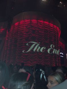 people standing in front of a red curtain with the words the end on it