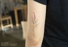 a woman with a tattoo on her arm has a lavender flower tattooed on her left arm