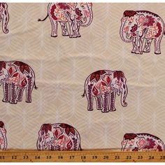 an elephant print fabric with red and pink flowers on it's back, next to a ruler