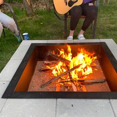 a person sitting in a chair next to a fire pit with a guitar on it