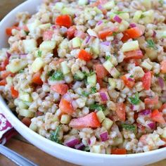 a white bowl filled with rice and veggies on top of a wooden table