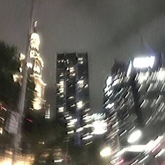 a blurry photo of some buildings in the city at night with street lights and traffic