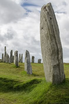 large rock formations in the middle of a grassy field with blue sky and white clouds