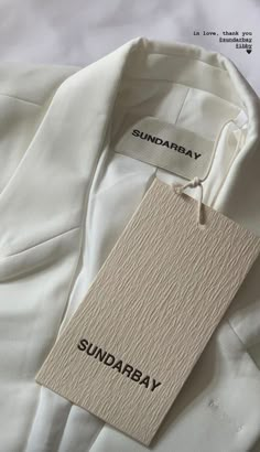 a white shirt with the word sunday on it and a tag hanging from its collar