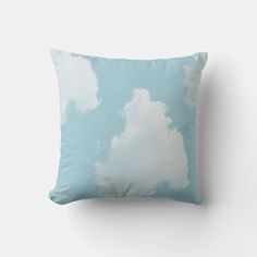 a blue pillow with white clouds in the sky on it's back side, sitting against a wall