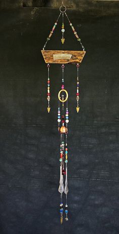 a wind chime hanging from the side of a wall with beads and feathers on it