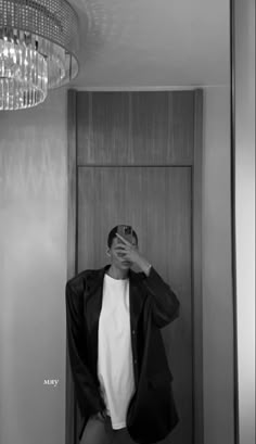 a man taking a selfie in front of a chandelier with his hands behind his head