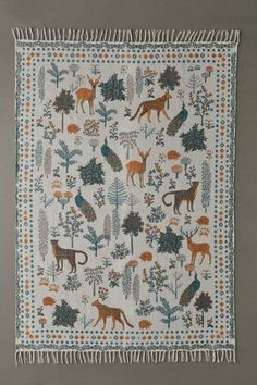 an embroidered wall hanging with various animals and trees on it, along with fringes