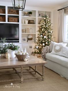 a living room filled with furniture and a christmas tree in front of a tv mounted on a wall