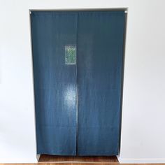 an open blue door in the corner of a room with wood floors and white walls