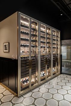 an empty wine cellar with many bottles in the glass doors and lights on the wall