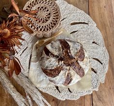 a loaf of bread sitting on top of a white doily next to dried flowers