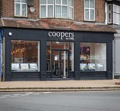 an empty street corner in front of a building with shops on the side and windows