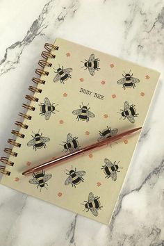 a notepad with bees on it and a pen resting on the cover next to it