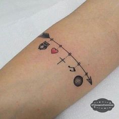 a woman's arm with an arrow, heart and other items tattooed on it