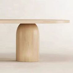 a round table with a wooden base on a plain surface in front of a white wall