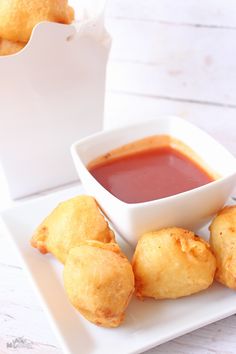 some fried food on a plate with dipping sauce in a small white bowl next to it