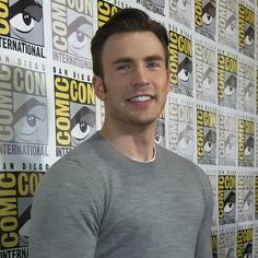 a man standing in front of a wall with comic books on it and looking at the camera