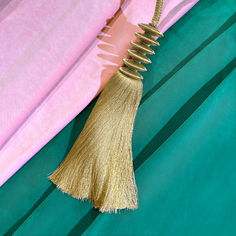 a gold tassel hanging from the side of a pink and green bed sheet with blue sheets