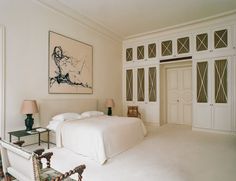 a bedroom with white walls and carpeted flooring has a large painting on the wall