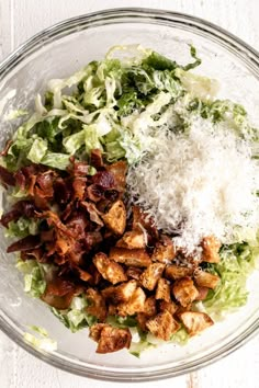 a salad with lettuce, bacon and parmesan cheese in a glass bowl