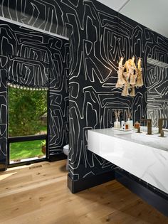 a bathroom with black and white wallpaper, wooden floors and two sinks in front of a large window