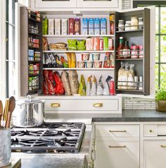 a kitchen with white cabinets and lots of food on the shelves in front of the stove