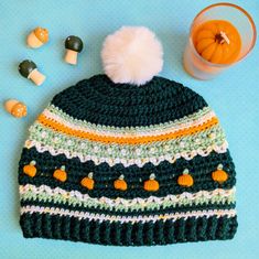 a crocheted hat with pumpkins and candy on the side next to it