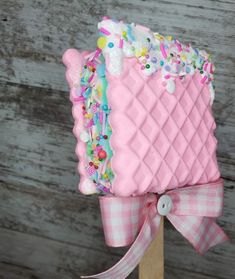 a pink cake with sprinkles on it sitting on top of a wooden stand