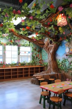 an empty classroom with tables and benches under a tree decorated with flowers on the ceiling