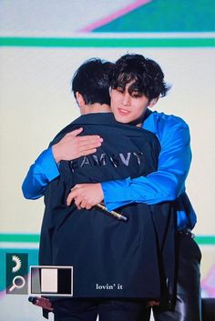 two young men hugging each other in front of a screen with the words love it written on it