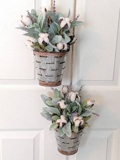 two metal buckets with flowers hanging from the side of a white door hanger