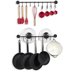 an assortment of pots and pans hanging on a wall with utensils attached