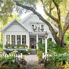 a white house surrounded by trees and flowers