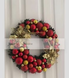 a christmas wreath hanging on the side of a door with balls and leaves around it